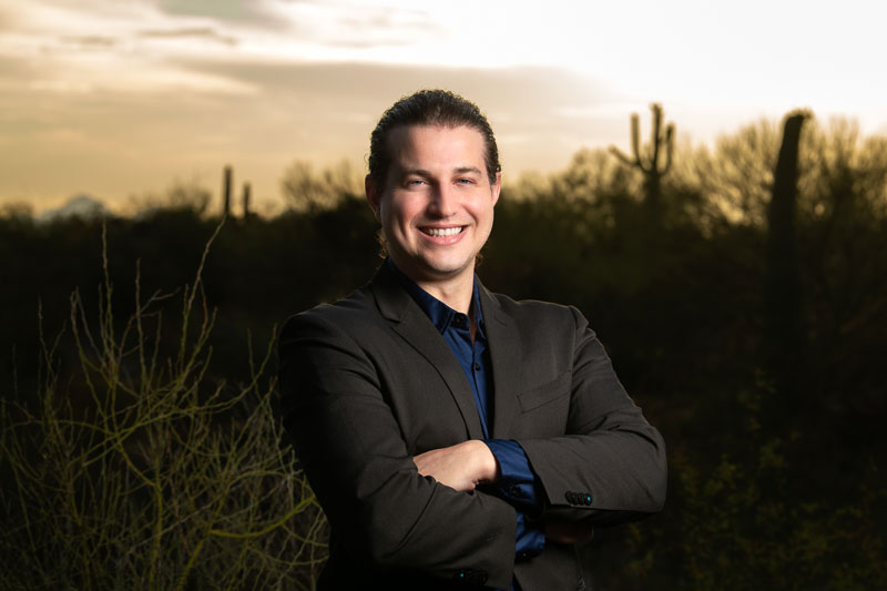 ODD Foundation president and CEO Alan Davis stands in the desert for a portrait with his arms crossed wearing a dark suit.
