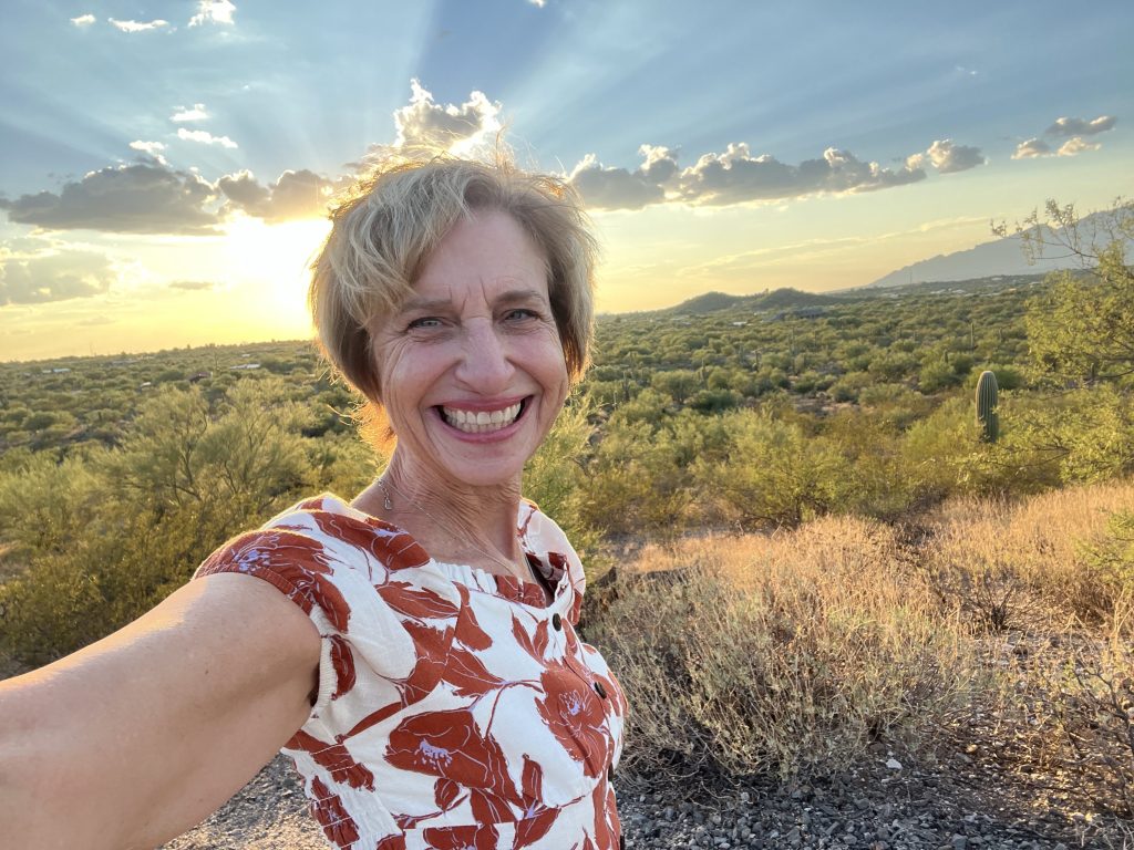 Director of Education Katherine A. Davis taking a selfie in Saguaro National Park at sunset wearing a floral blouse.